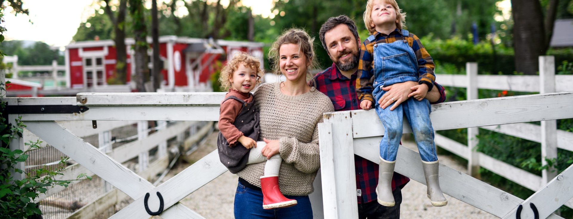 Portrait of happy family with small children standing on farm.