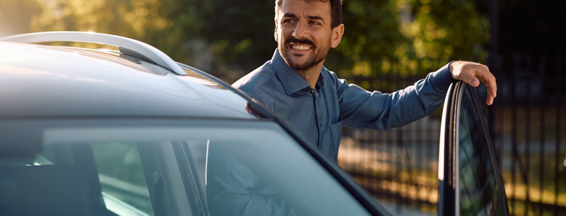 Happy man getting out of his car on a parking lot. Copy space.