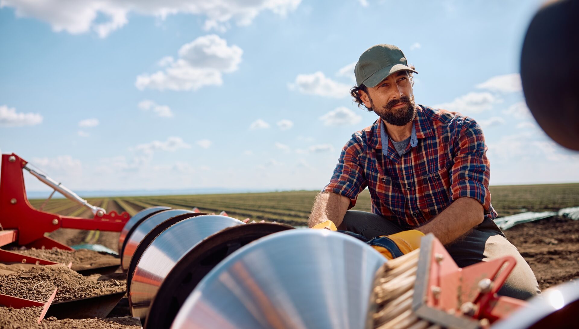 Pensive agronomist setting up disc harrows on a tractor while plowing the land.